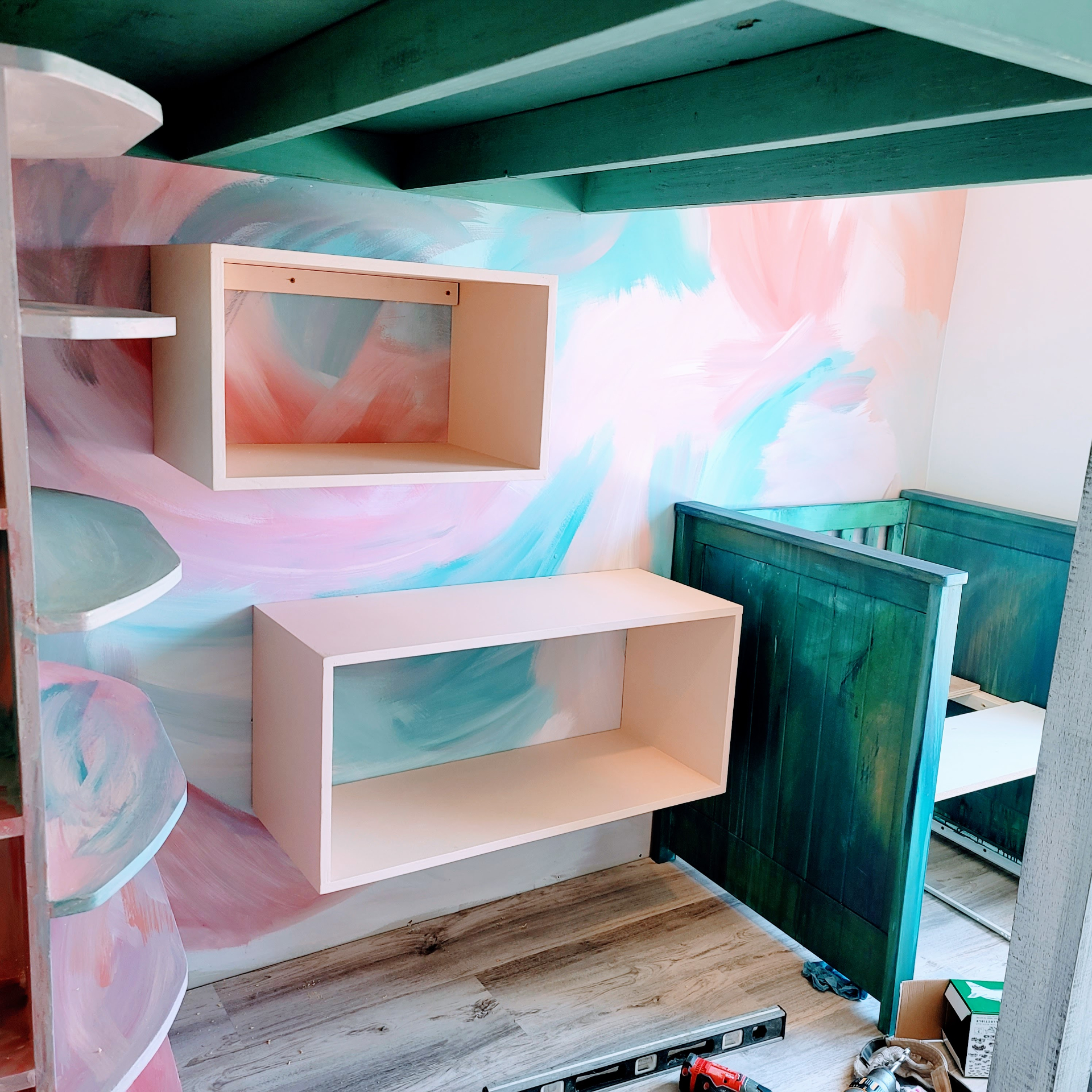 Mid-build — floating shelves and the hand-painted mural taking shape.