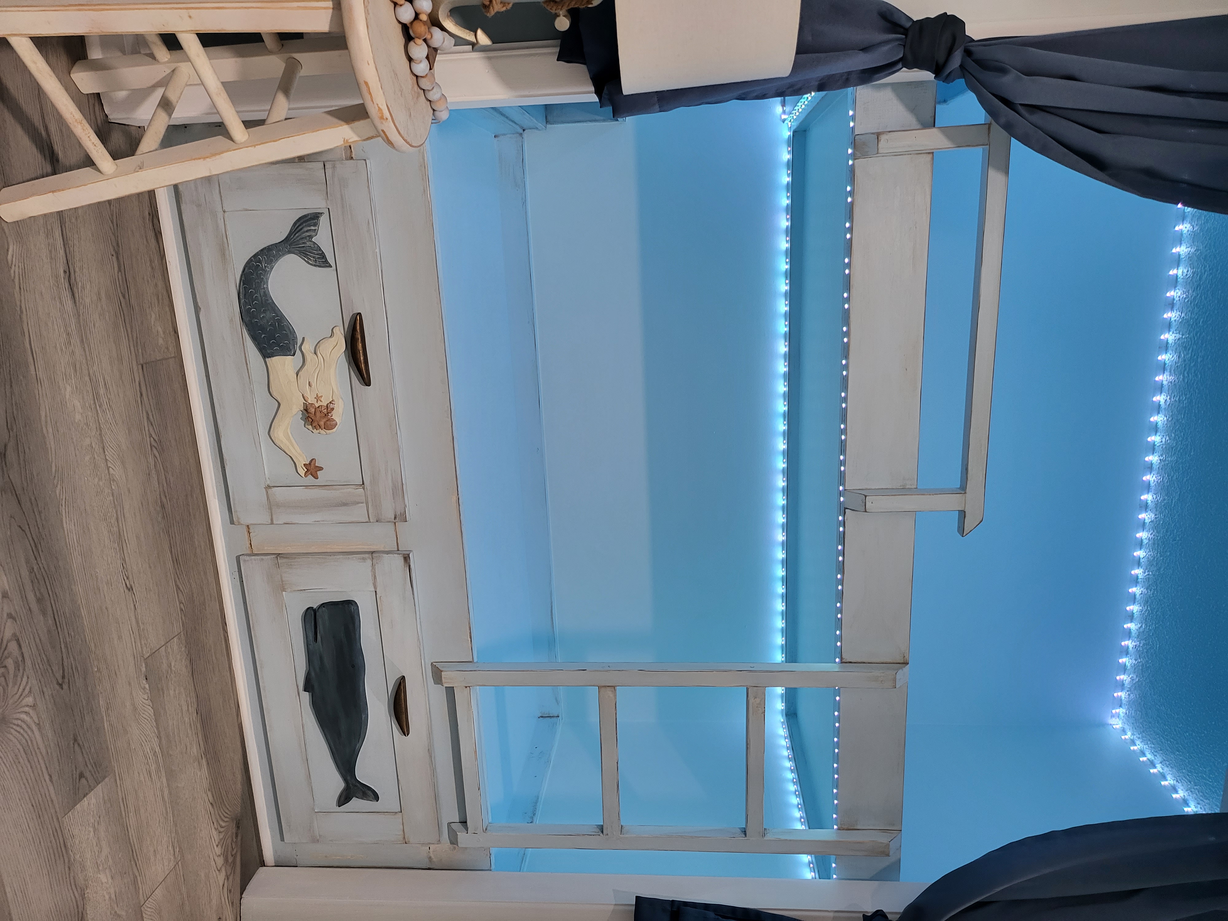The finished bunk nook — soft ocean blue, weathered white and a warm underwater glow.
